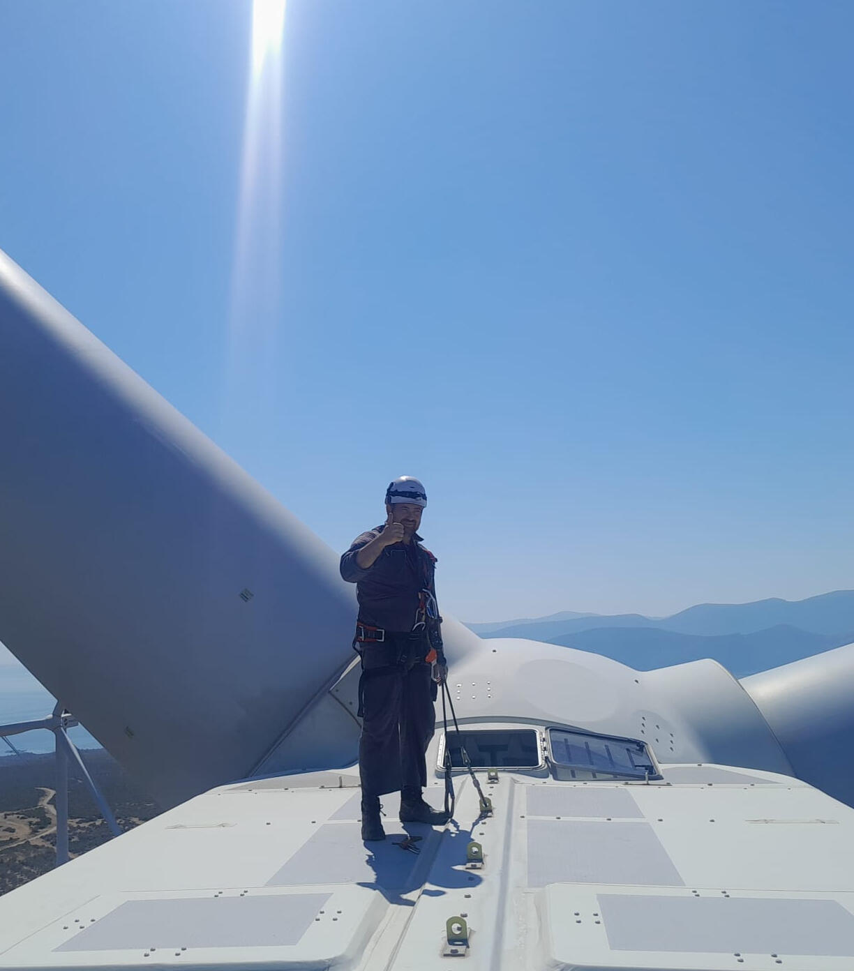 Wind technician standing on a turbine nacelle in full harness